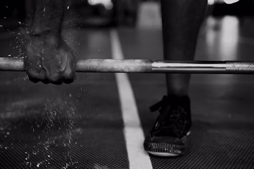Chalked hands driving a loaded barbell through a clean