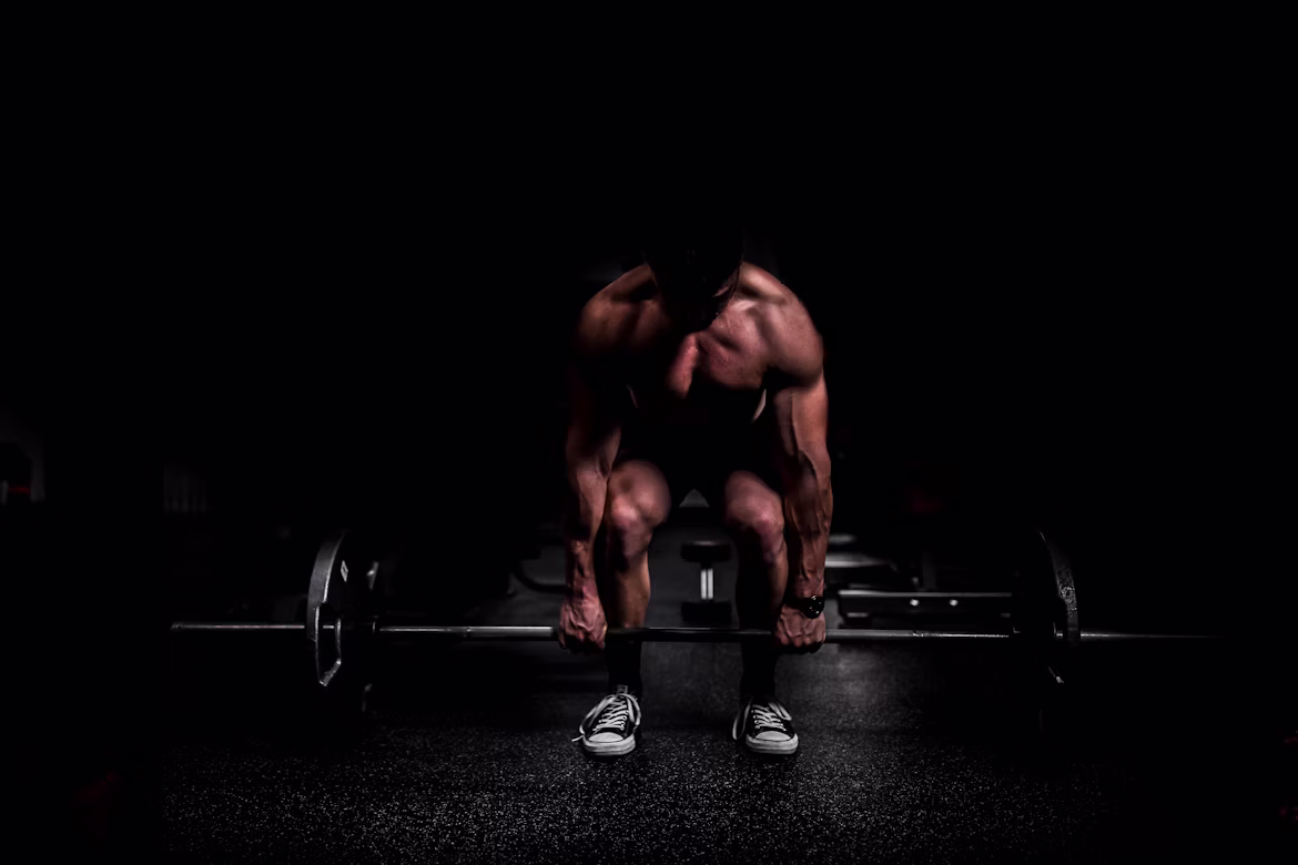 Lifter at the top of a heavy deadlift with chalk dust in dramatic side light