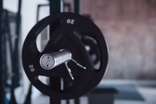 Hands loading another plate onto a barbell under dramatic light